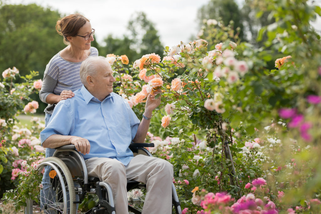 woman with elderly wheelchair bound man in garden
