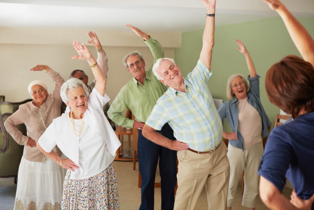 Group of senior citizens doing gentle stretching exercises