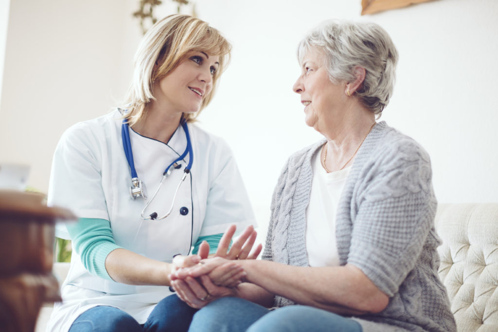 Female health professional speaking to elderly adult woman