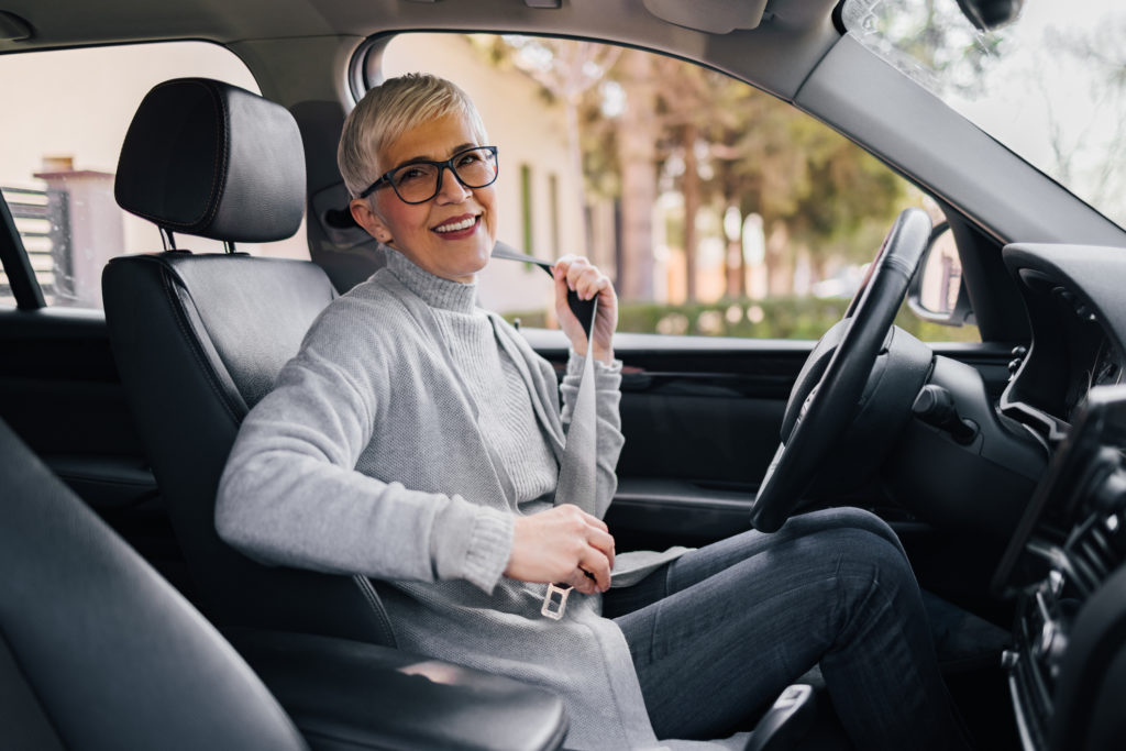 Older woman in car putting on seatbelt